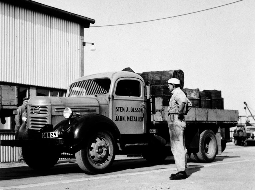 Historic black and white picture of man in front of truck