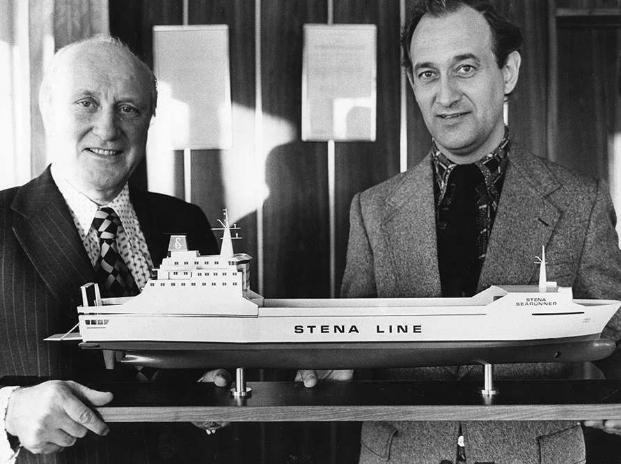 Two men holding a model of a ship