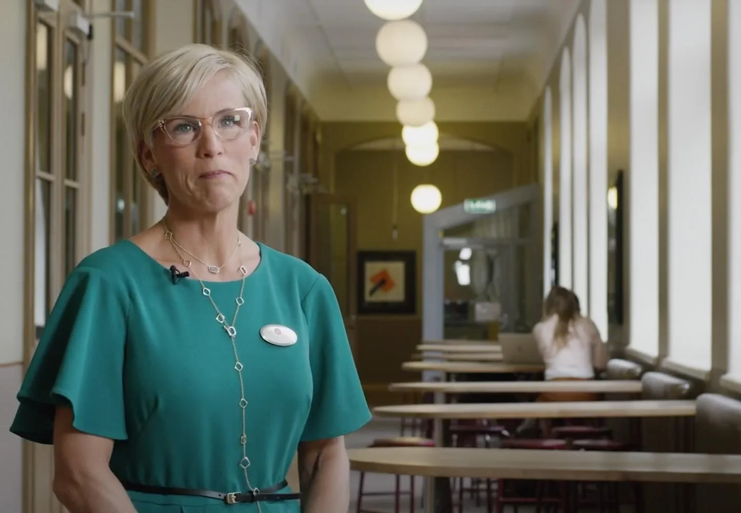 Blonde woman in green dress at a school