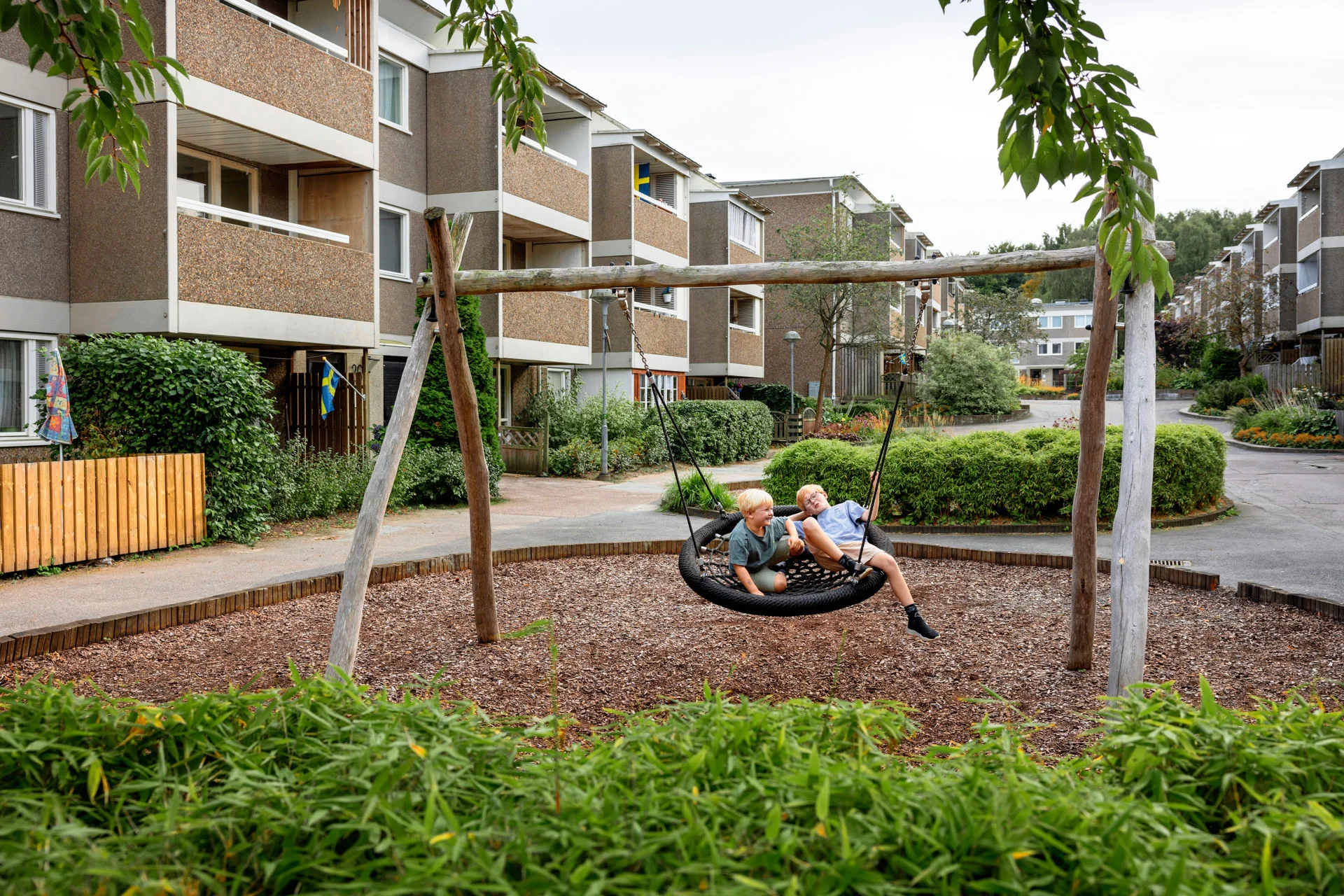 Two kids in a big swing in a residential area