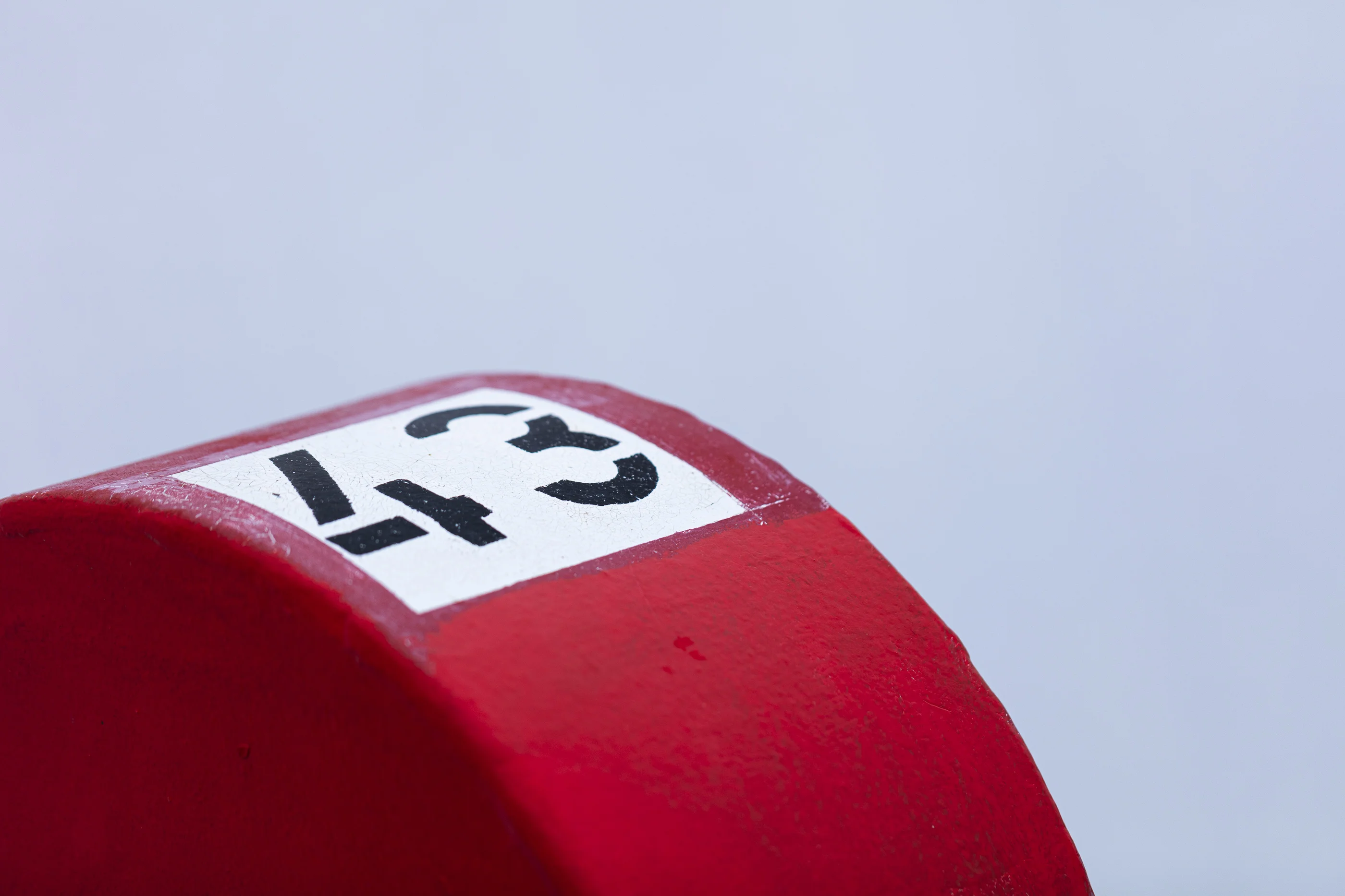 Close-up of a red surface with a white label displaying a black number 43, set against a blurred light background.